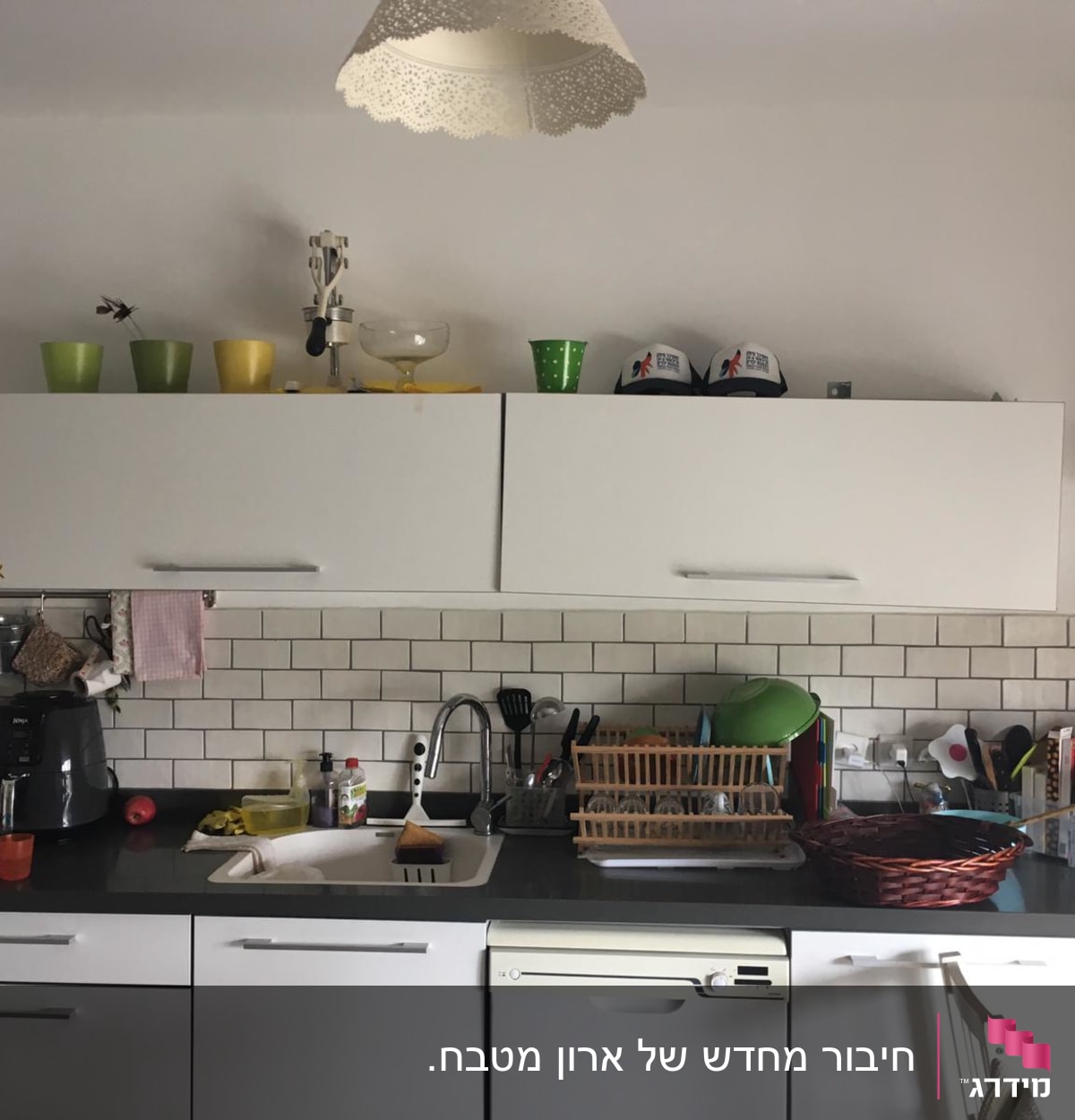 מטבח עם כלים על השיש וארונות לבנים